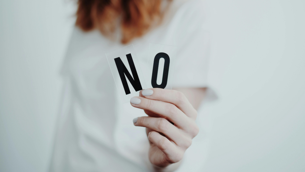Une femme qui montre les lettres N et O pour dire non.